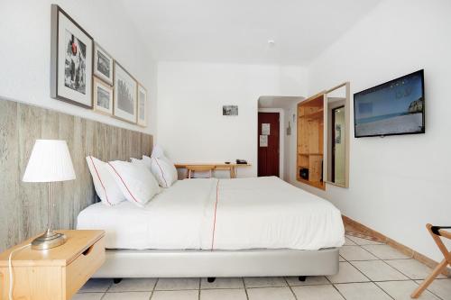 a bedroom with a white bed and a tv at Hotel Carvoeiro Plaza in Carvoeiro