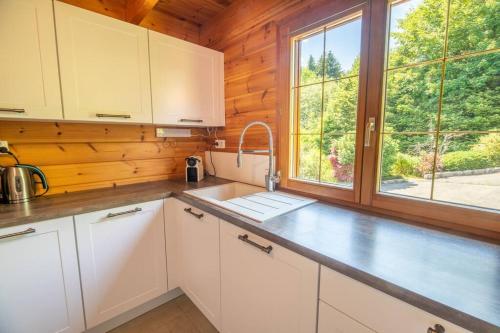 a kitchen with white cabinets and a large window at Le Chant du Ruisseau SPA - Sauna in Le Tholy