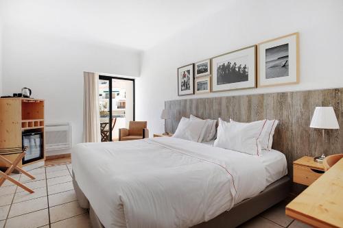 a bedroom with a large bed and a living room at Hotel Carvoeiro Plaza in Carvoeiro
