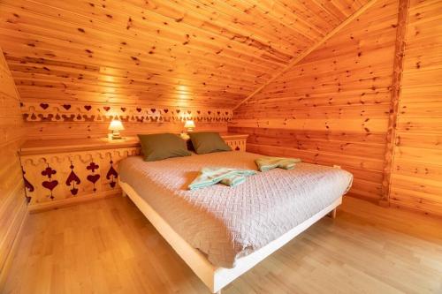 een slaapkamer met een bed in een houten hut bij Le Chant du Ruisseau SPA - Sauna in Le Tholy