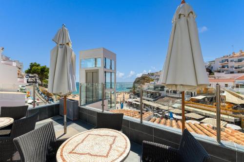 a patio with tables and umbrellas and the ocean at Hotel Carvoeiro Plaza in Carvoeiro