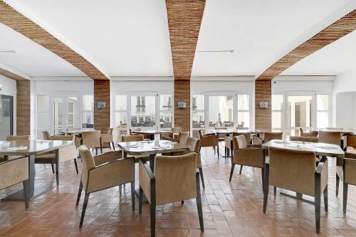 Hotel Carvoeiro Plaza في كارفويرو: غرفة طعام مع طاولات وكراسي ونوافذ