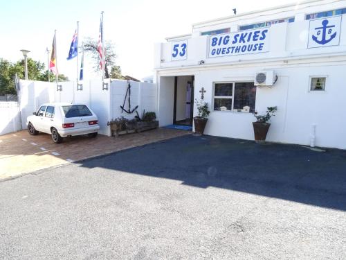 a white building with a car parked in front of it at Big Skies Guesthouse in Gordonʼs Bay