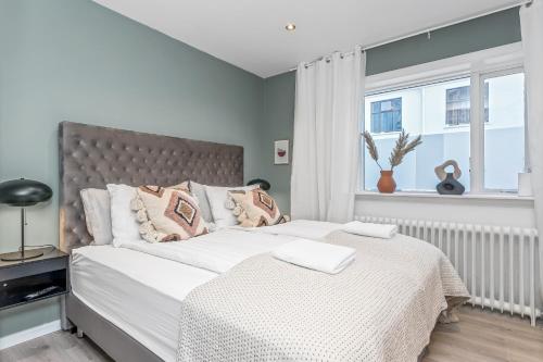 1 dormitorio con 1 cama con sábanas blancas y ventana en Venture Vacation-Reykjavík Center, King bed, 65" TV with Netflix en Reikiavik