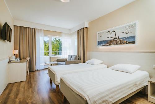 a hotel room with two beds and a chair at Hestia Hotel Strand in Pärnu