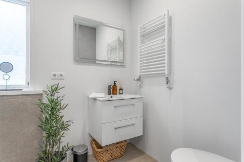 a white bathroom with a sink and a mirror at Venture Vacation-Reykjavík Center, King bed, 65" TV with Netflix in Reykjavík