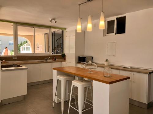 ベナルマデナにあるSiriana Suites 101, 001の白いキャビネットとスツール付きの木製の島が備わるキッチン