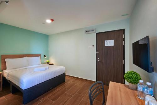 a bedroom with a bed and a table and a television at ZONE Hotels, Eco Grandeur in Bandar Puncak Alam