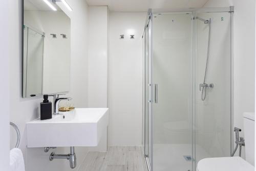y baño blanco con lavabo y ducha. en Apartamentos LA PELUSA, en Málaga