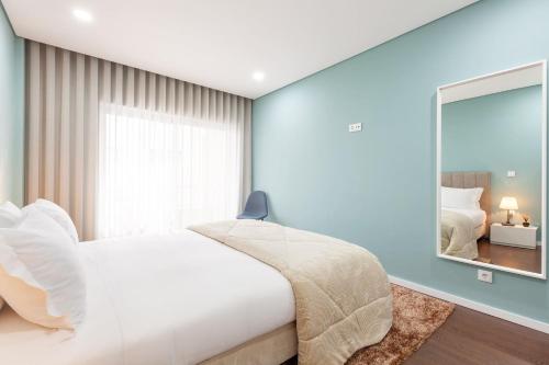 una camera da letto con un letto bianco e un grande specchio di Libertà Lodge Apartment - Minho's Guest a Braga