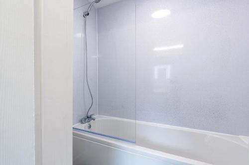 een badkamer met een bad en een glazen douchedeur bij Stylish Home with Garden, Free Street Parking in Hull