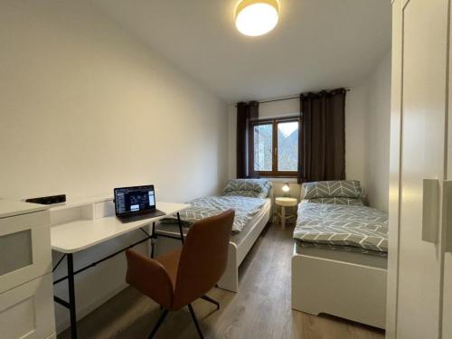 een kamer met een bed en een bureau met een laptop bij moderne Ferienwohnung mit Berg- und Isarblick in Mittenwald