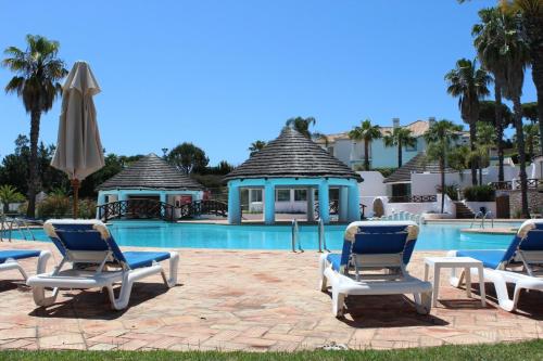 un gruppo di sedie a sdraio e una piscina di Tulio 2 Bedroom Luxury Apartment located in Encosta Do Lago a Quinta do Lago