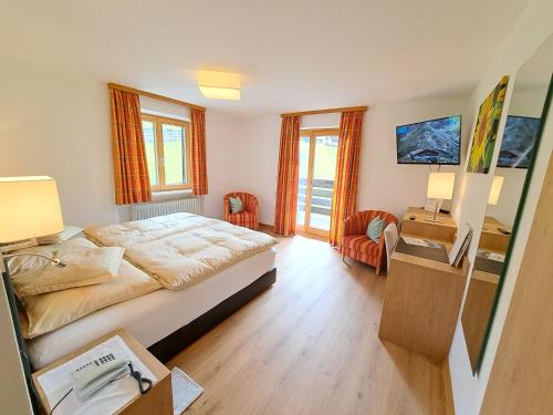 sypialnia z łóżkiem, biurkiem i krzesłami w obiekcie Pension Mallaun w Lech am Arlberg