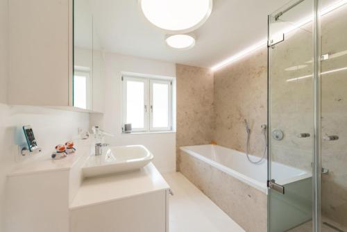 a white bathroom with a sink and a shower at luxuriöse Ferienwohnung in Mittenwald für Genießer in Mittenwald