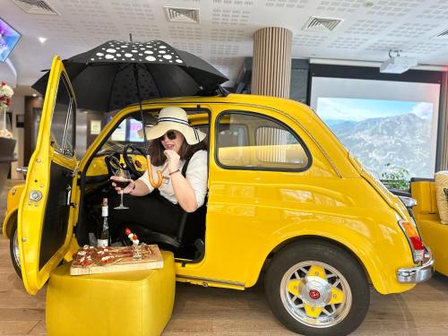 a woman sitting in a yellow car with an umbrella at Best Western Plus Thionville Centre in Thionville