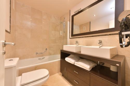 ein Badezimmer mit zwei Waschbecken, einer Toilette und einer Badewanne in der Unterkunft Apartamento con vistas al mar y parking incluido in Torrox Costa