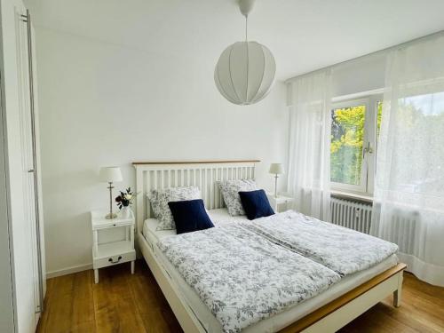 a white bedroom with a large bed with blue pillows at Ferienwohnung Blau in Bad Zwischenahn