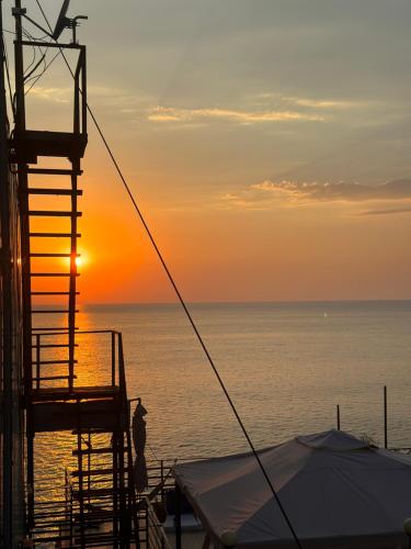une personne debout sur le pont d'un bateau au coucher du soleil dans l'établissement Blue Apartment, à Gonio