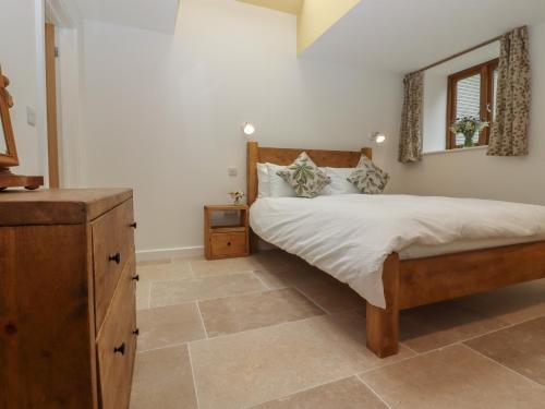 a bedroom with a bed with a dresser and a mirror at Swallows Lodge in Edenbridge