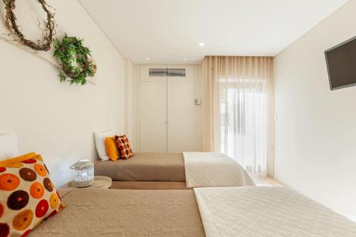 a bedroom with two beds and a television at Apartamento Lírio - Minho's Guest in Braga
