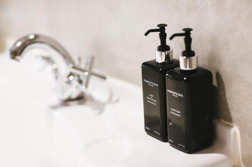 two black soap bottles sitting on a bathroom sink at Cherry Blossom - Backup Power Inverter in Ceres