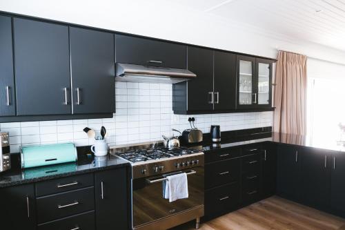 a kitchen with black cabinets and a stove top oven at Cherry Blossom - Backup Power Inverter in Ceres