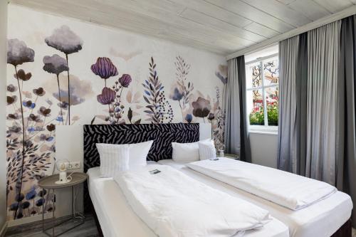 1 dormitorio con 2 camas y pared de flores en Flair Hotel zum Storchen, en Bad Windsheim