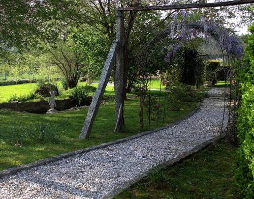 a garden with an arch and a gravel path at As Seis Chemineas in San Xulián de Sales