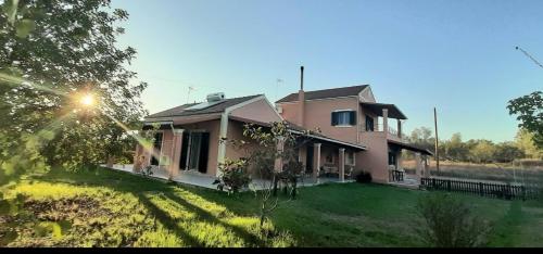a large pink house with a grass yard at Lonelia's Family Homes in Lefkímmi