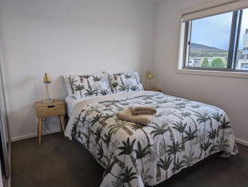 1 dormitorio con 1 cama con colcha de temática vegetal en Modern & Relaxed Apartment, Great Views @Wright, en Weston Creek