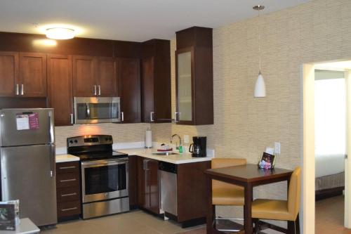 a kitchen with wooden cabinets and stainless steel appliances at Residence Inn by Marriott Savannah Airport in Savannah