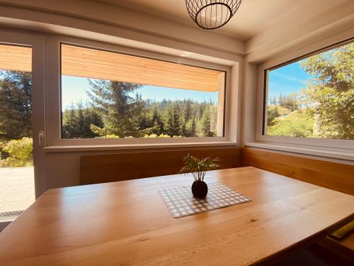 a dining room with a table and two windows at NORDIC Apartamente Păltiniș in Păltiniş