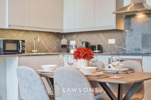 a wooden table with chairs and a vase of flowers on it at 3-Bed, 3-Bath Apartment with Southsea Common Views in Portsmouth