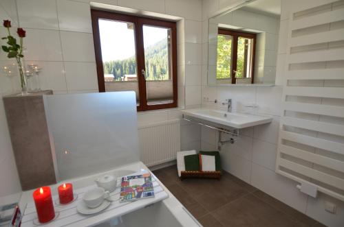W białej łazience znajduje się umywalka i lustro. w obiekcie Pension Mallaun w Lech am Arlberg