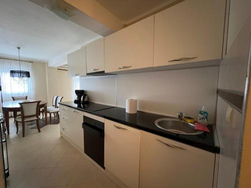 a kitchen with white cabinets and a sink and a table at Przno apartment in Budva