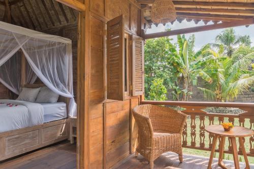 Nunu Bali Eco Friendly Retreat في تشانغو: غرفة نوم بسرير وطاولة على شرفة