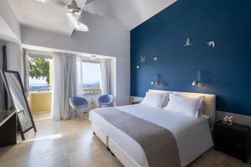 a bedroom with a large bed and a blue wall at The Majestic Hotel in Fira