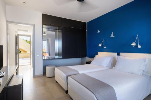 a bedroom with a white bed and a blue wall at The Majestic Hotel in Fira