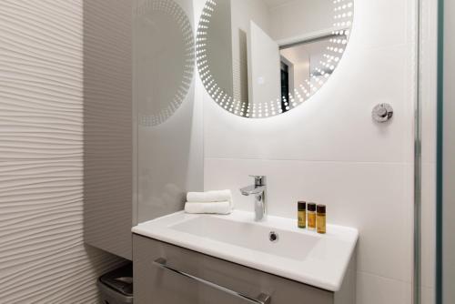 une salle de bain blanche avec un lavabo et un miroir dans l'établissement Fettolina, à Cannes