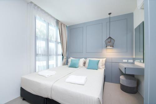 ein Schlafzimmer mit einem weißen Bett mit blauen Wänden und einem Waschbecken in der Unterkunft 2bdr Apartment near Surin beach #302 in Ban Lum Fuang