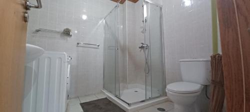 a white bathroom with a shower and a toilet at Prédio Mekuí in São Tomé