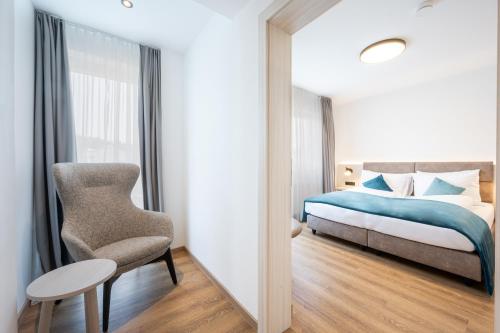 ein Schlafzimmer mit einem Bett und einem Stuhl neben einem Fenster in der Unterkunft Hotel Villa Flora in Velden am Wörthersee