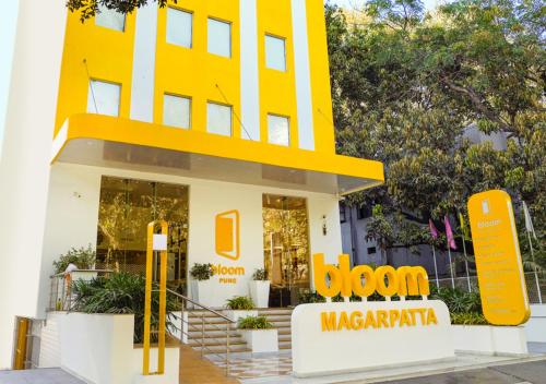 un edificio amarillo con un cartel delante en Bloom Hotel - Magarpatta, en Pune