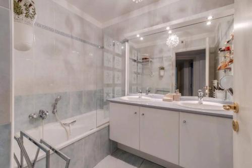 une salle de bain avec deux lavabos, une baignoire et un miroir dans l'établissement Magnifique 4 pers plage à pied, à Fréjus