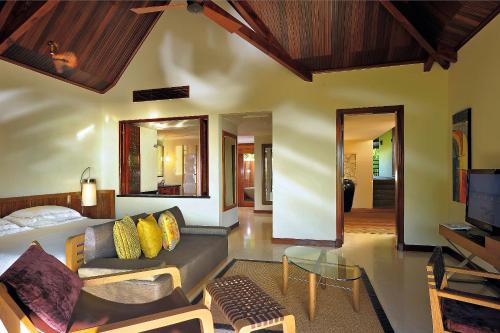 a living room with a couch and a table and a tv at Constance Lemuria in Grand'Anse Praslin