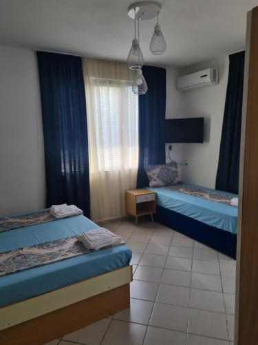 two beds in a room with blue curtains at Къща за гости СТЕЛА in Primorsko