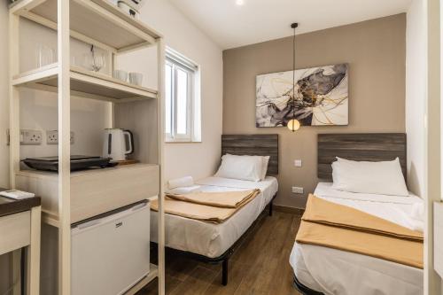 Habitación pequeña con 2 camas y estante en Studio apartment with twin beds & kitchenette at the new Olo living 24, en Paceville