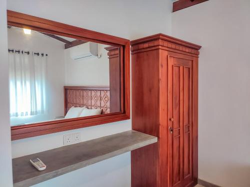 a mirror and a wooden cabinet in a room at Peacock Village Pinnawala in Pinnawala