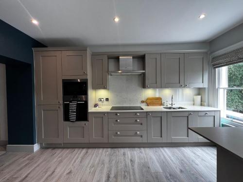 uma grande cozinha com armários brancos e um lavatório em Luxury apartment Berkshire em Binfield